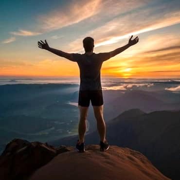 Deliberate Living: Align Actions with Your Ambitions Man on top of mountain looking into the distance