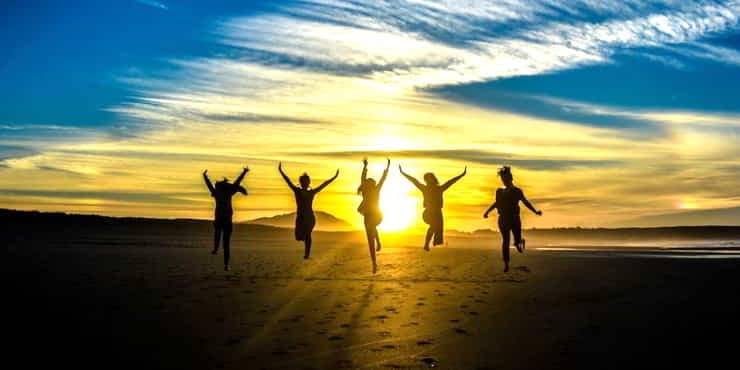5 silhouettes on a beach at sunset